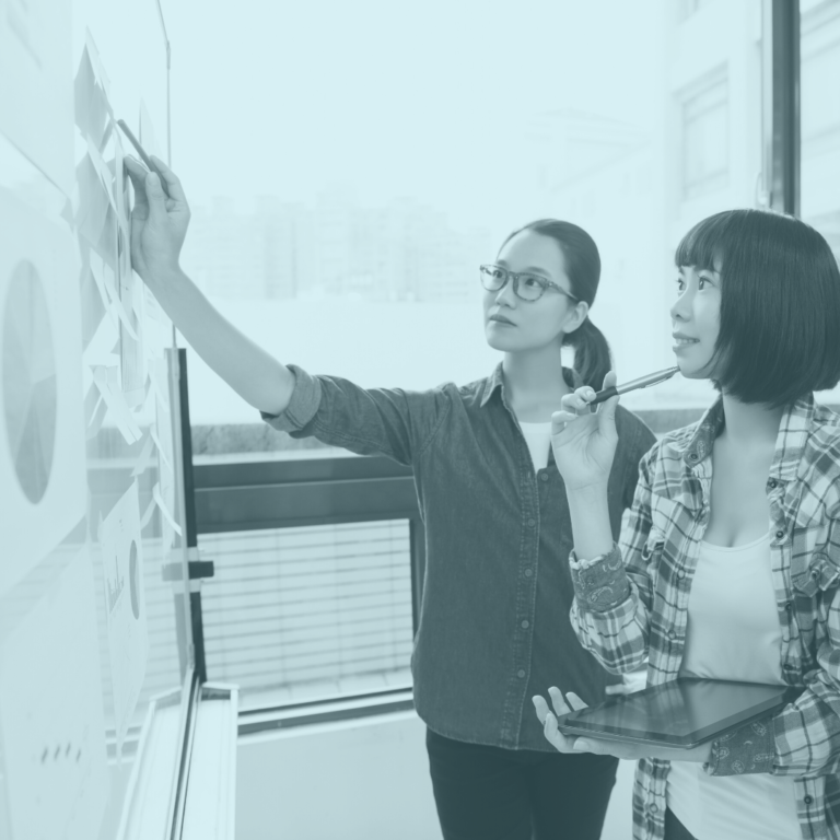 Two women at white board working