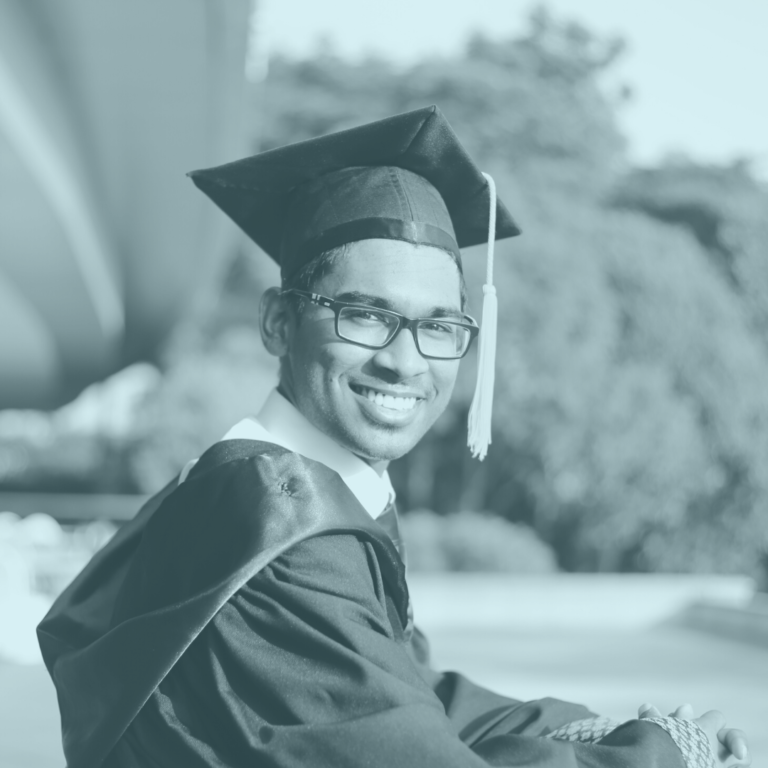 Young man in graduate outfit and hat smiling