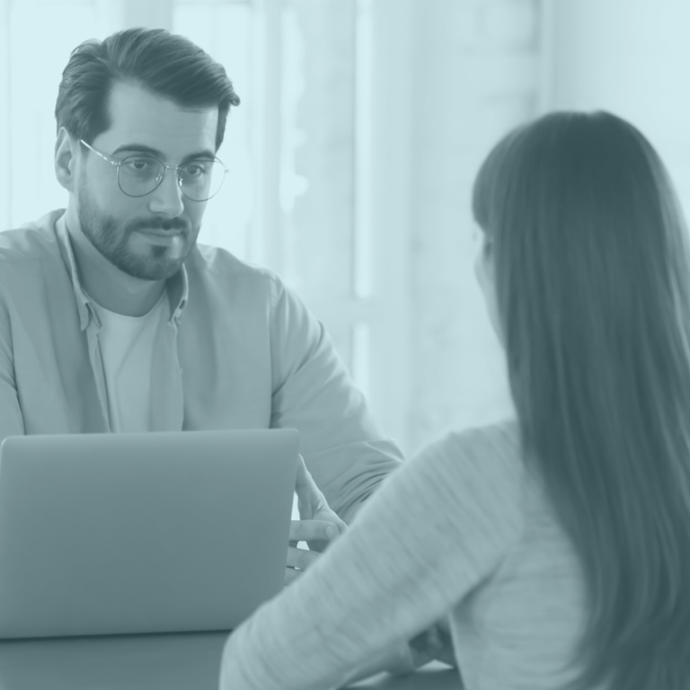 Man sitting at a screen across from a woman