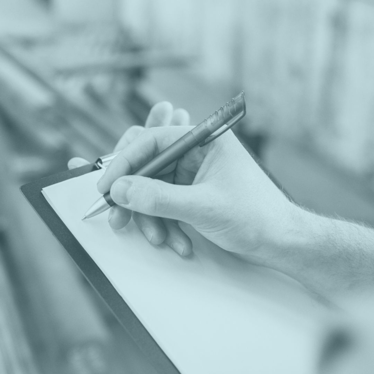 Blue toned photo of a quality check with a person's hand writing on a clipboard