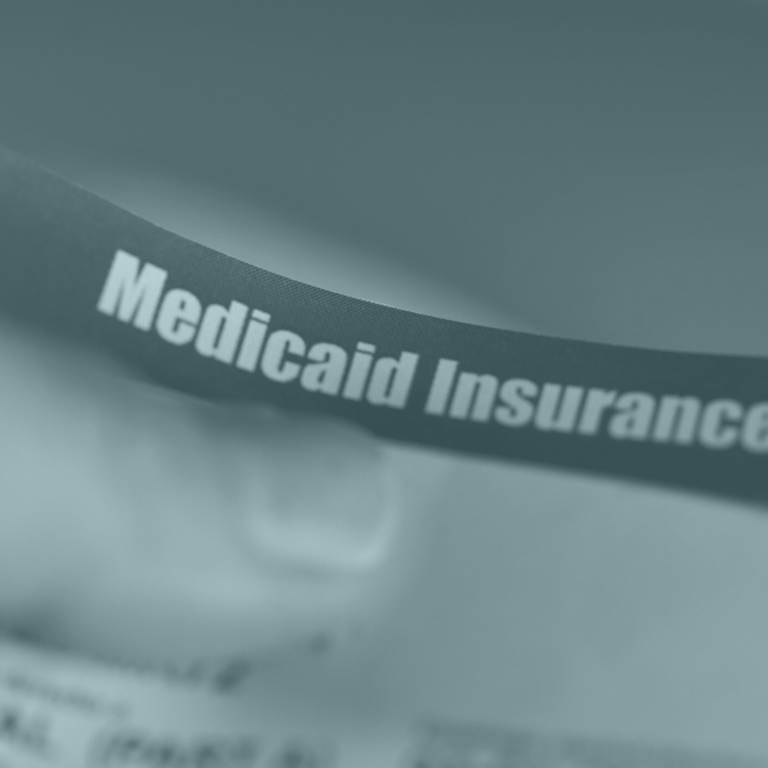 Image of a thumb on paper that reads medicaid insurance to signify health plans