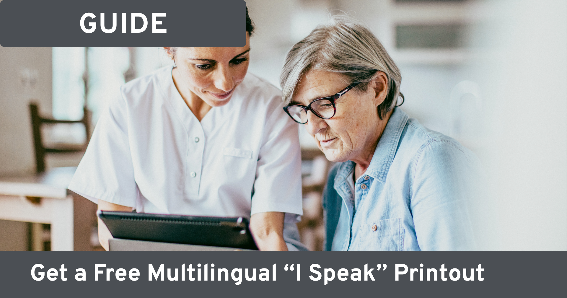 "Two women looking at a tablet together, one pointing to the screen as she shows the other something. Text on image reads: 'Guide; get a free multilingual I Speak printout.'